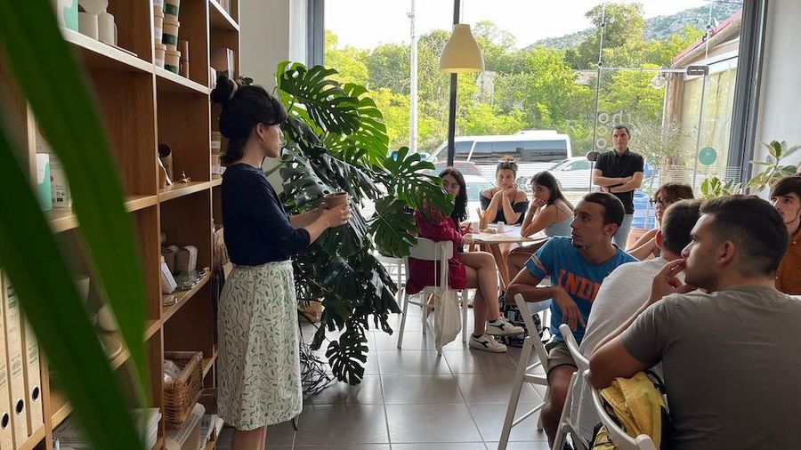 tourists sitting at the tables and listening to a girl giving a tour at Rhoeco Fine Organic Goods
